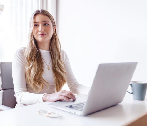 Young blond woman working on her laptop at the office